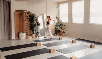 A serene yoga studio with several mats arranged neatly, surrounded by plants and soft natural light filtering through the windows.