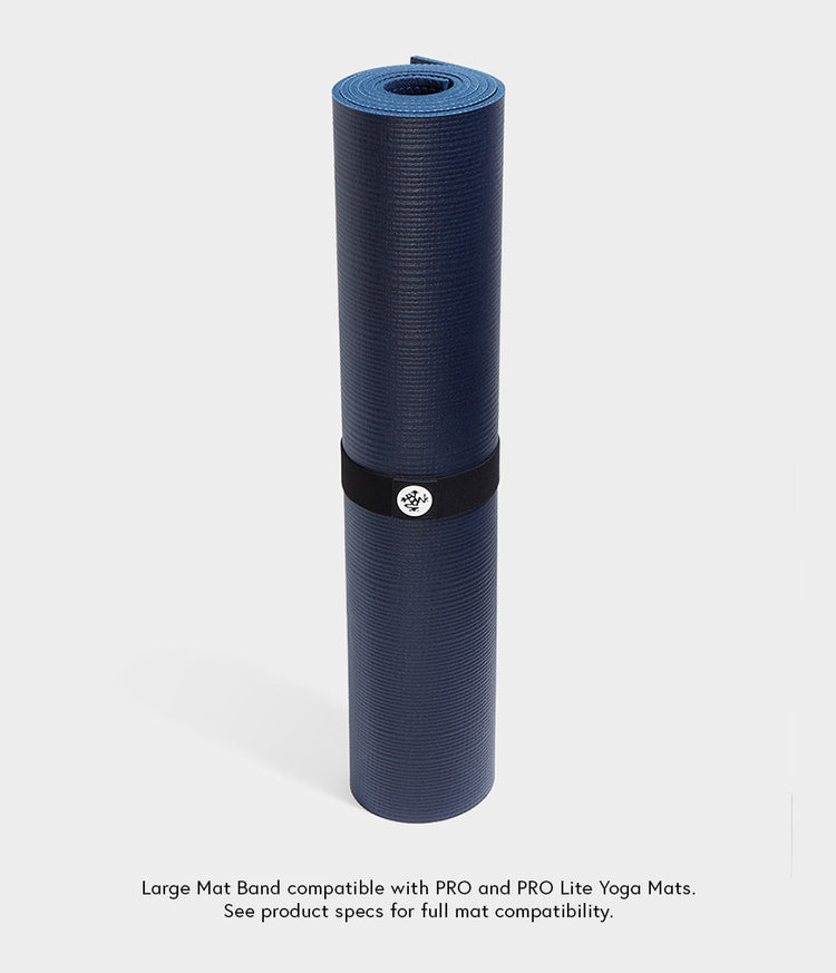 Sangle pour tapis Manduka maintenant un tapis de yoga bleu foncé roulé, avec une bande élastique noire et un badge portant le logo. Compatible avec les tapis de yoga PRO et PRO Lite.