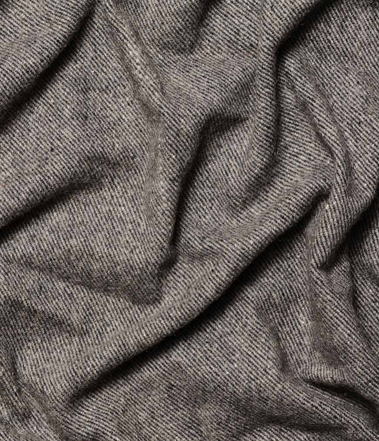 Close view of a draped gray woven recycled wool blanket with a soft textured surface and natural folds from Manduka